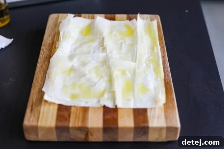 Phyllo dough sheets lightly sprayed with olive oil, showing a glossy, even coating