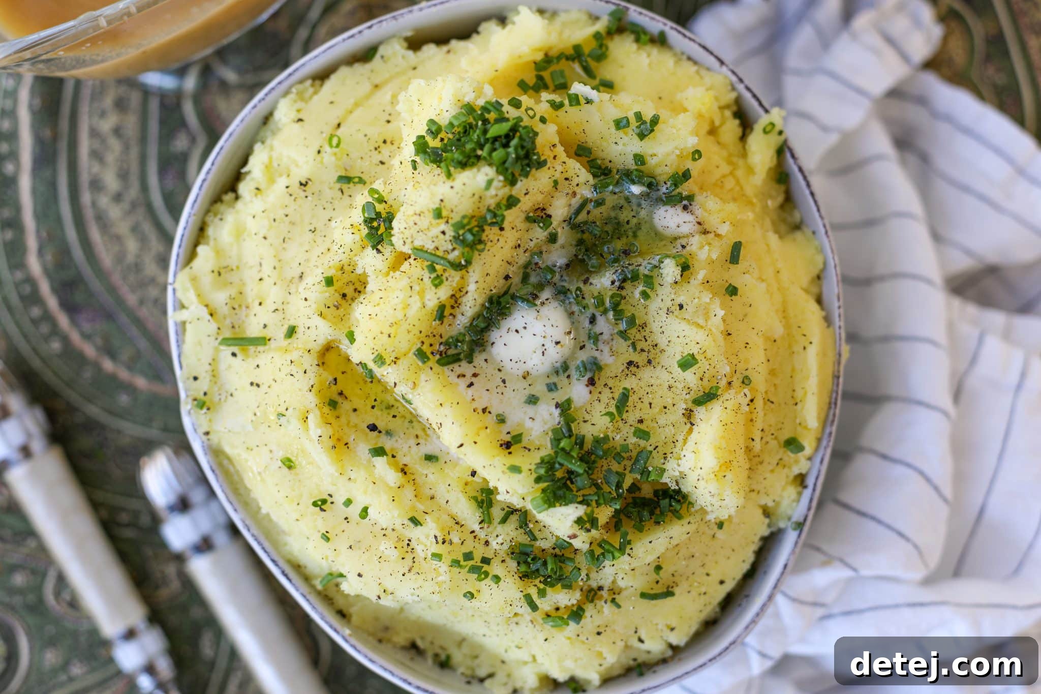 Creamy mashed potatoes in a bowl, topped with fresh chives.