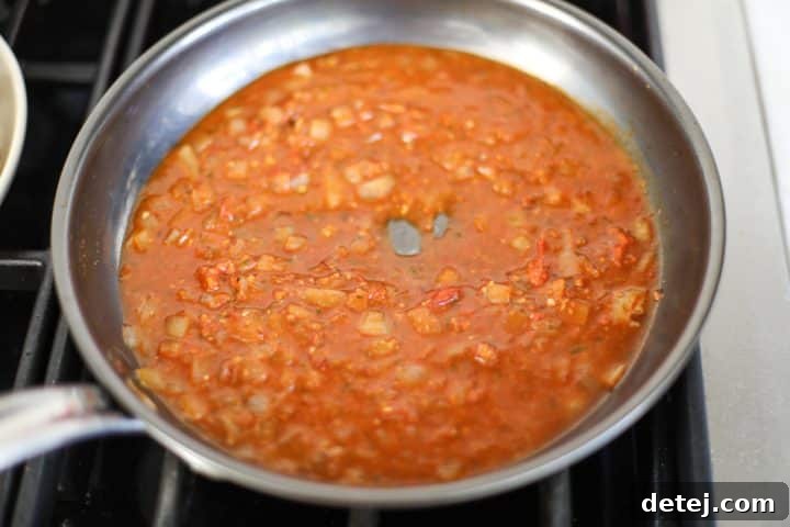 Low sodium chicken broth being poured into the pan to deglaze, releasing all the rich browned bits.