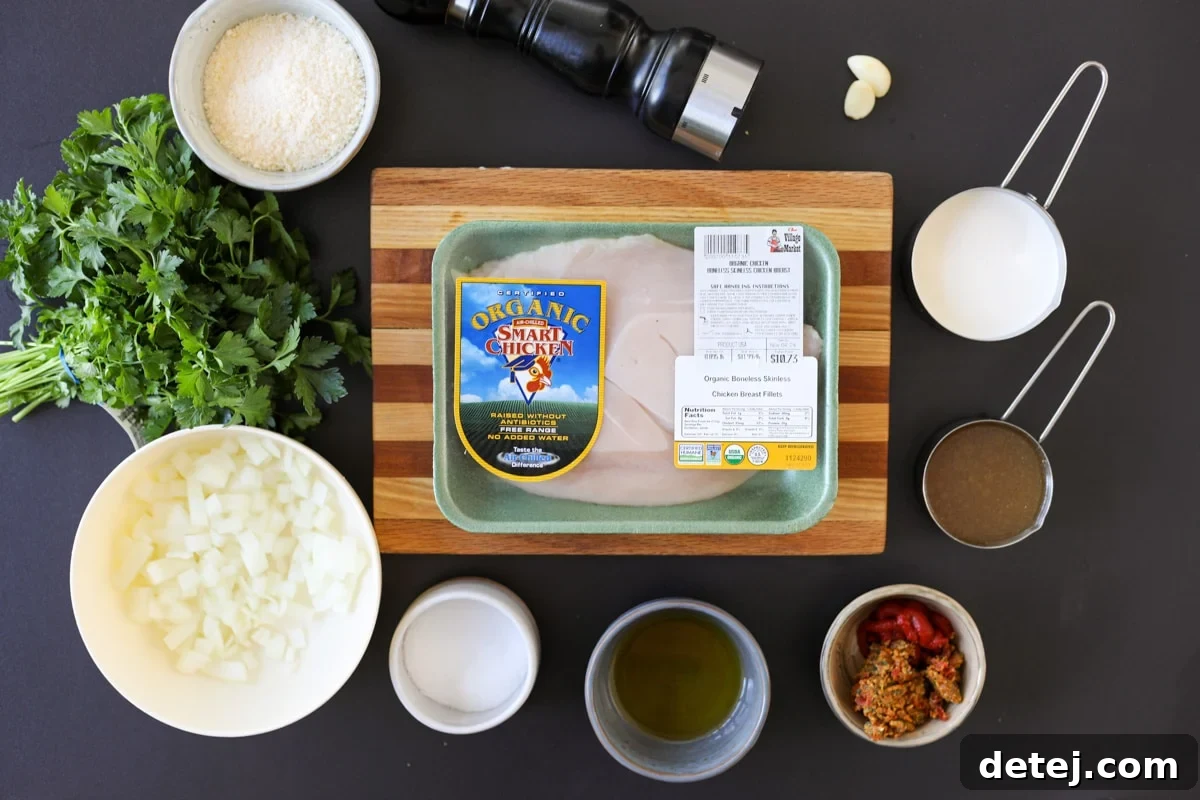 A curated selection of fresh ingredients ready for the creamy pesto chicken: chicken breasts, onions, garlic, tomato paste, heavy cream, and sun-dried tomato pesto.