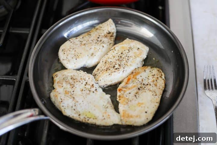 Thin chicken cutlets searing to golden perfection in a hot nonstick pan with avocado oil.