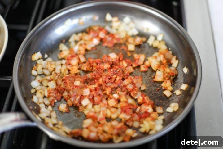 Sautéed onions and garlic mixed with tomato paste and sun-dried tomato pesto, caramelizing in the pan.