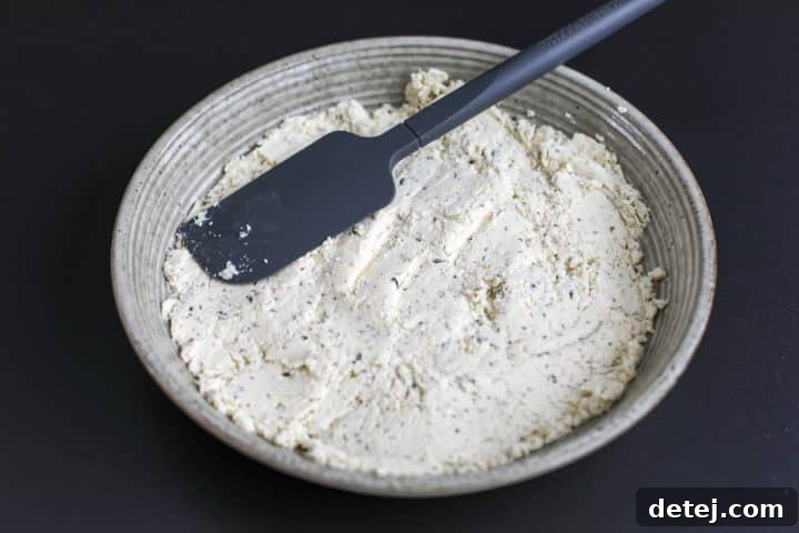 The Boursin cheese now evenly spread across the bottom of the serving bowl, forming a smooth, thin layer.