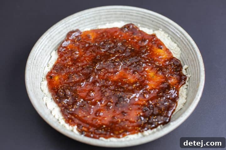 The fig jam now smoothly spread into a thin layer over the Boursin cheese in the serving bowl.
