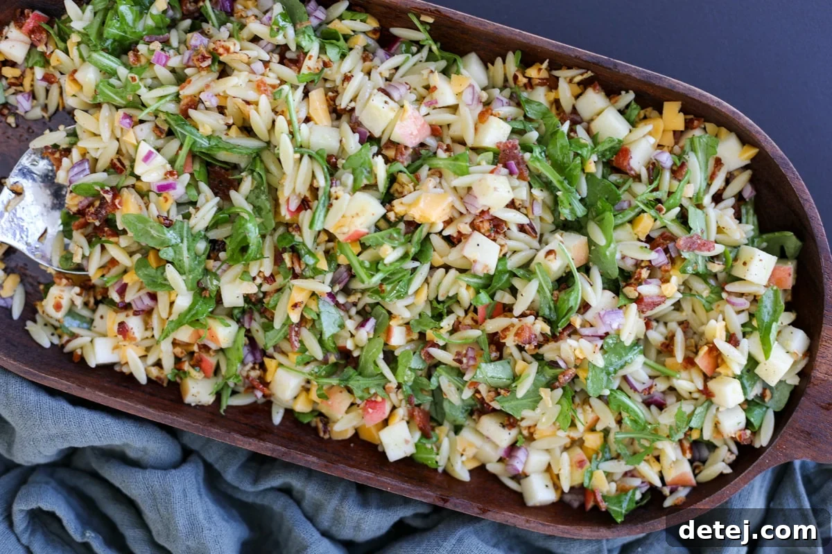 Chopped Fall Pasta Salad, served in a beautiful wooden bowl, showcasing vibrant ingredients like pasta, greens, bacon, apples, and cheese.