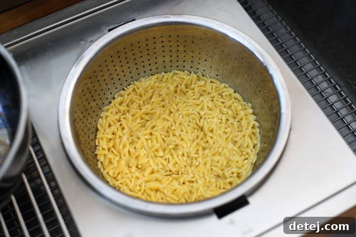 Cooked orzo pasta drained in a colander, ready for the salad.