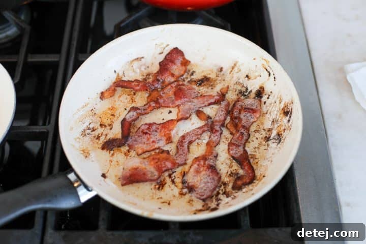 Pan-fried bacon strips cooling on a paper towel-lined plate.
