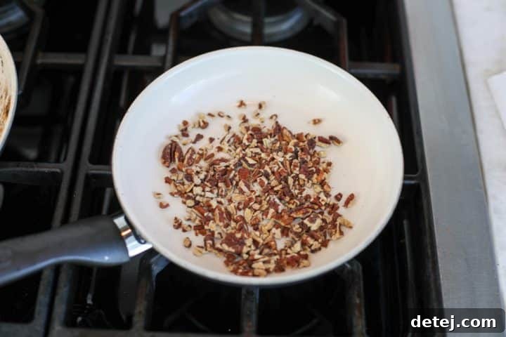 Pecan halves being toasted in a pan on the stovetop.