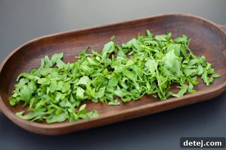 Fresh baby arugula leaves at the bottom of a large mixing bowl.
