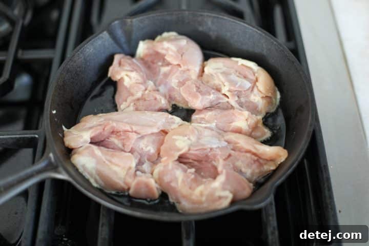 seasoned chicken thighs in the pan sautéing.