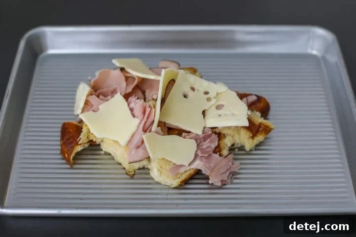 Swiss cheese added to the torn pretzel roll and ham.