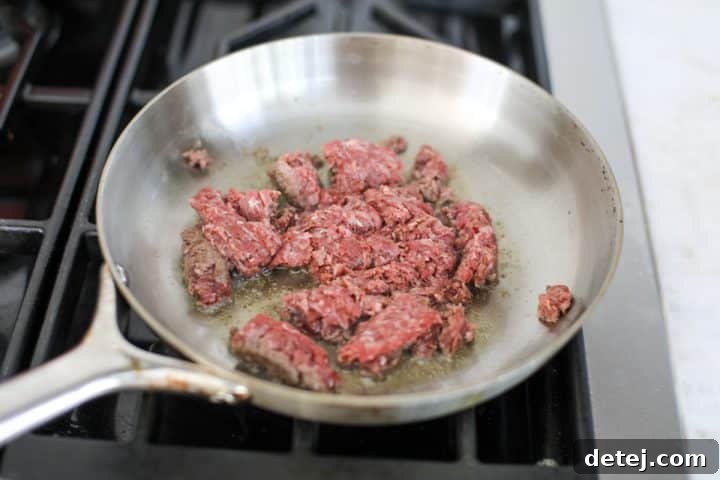 Effortless 20-Minute Turkish Beef Bowl 6 Ground beef cooking in a pan with a tablespoon of avocado oil over medium-high heat, beginning to brown.