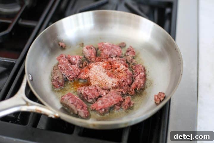 Effortless 20-Minute Turkish Beef Bowl 7 Ground beef in a pan, now seasoned with cumin, onion powder, and paprika, sautéing until browned and cooked through.