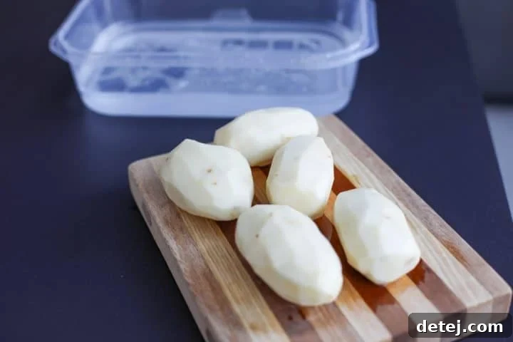 peeled potatoes in a cutting board.