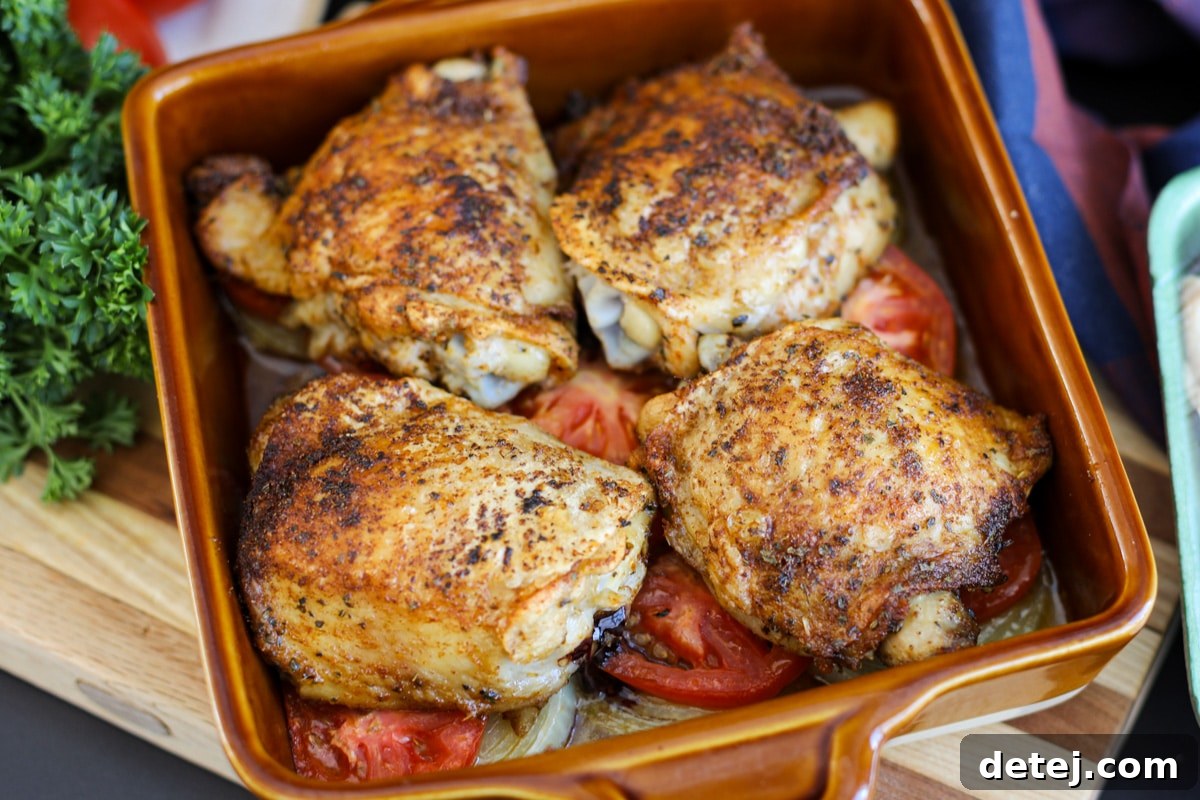 oven baked chicken thighs hot from the oven, served with fresh herbs.