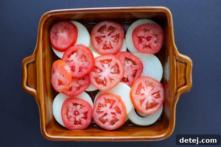 onions and tomatoes layered in a baking dish.