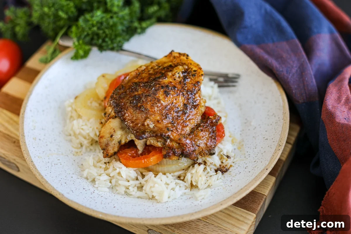 one perfectly baked chicken thigh on a plate, garnished.