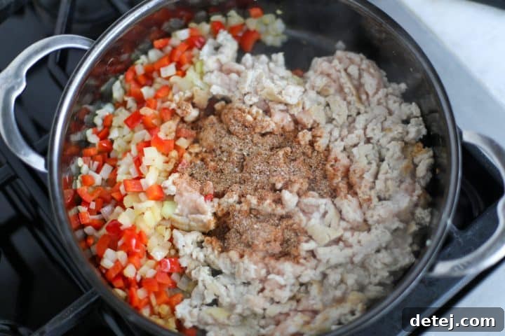 seasonings in a pan with ground chicken, onions and peppers.