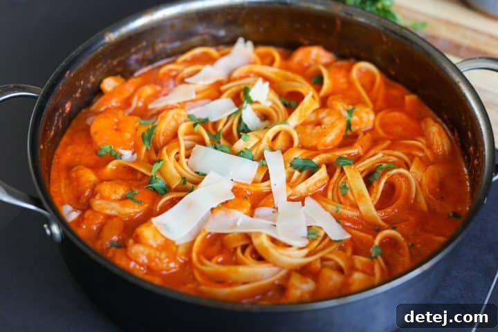 Smoky Red Pepper Shrimp Pasta 14 Finished shrimp pasta in a pan, garnished with shaved parmesan cheese and fresh parsley.