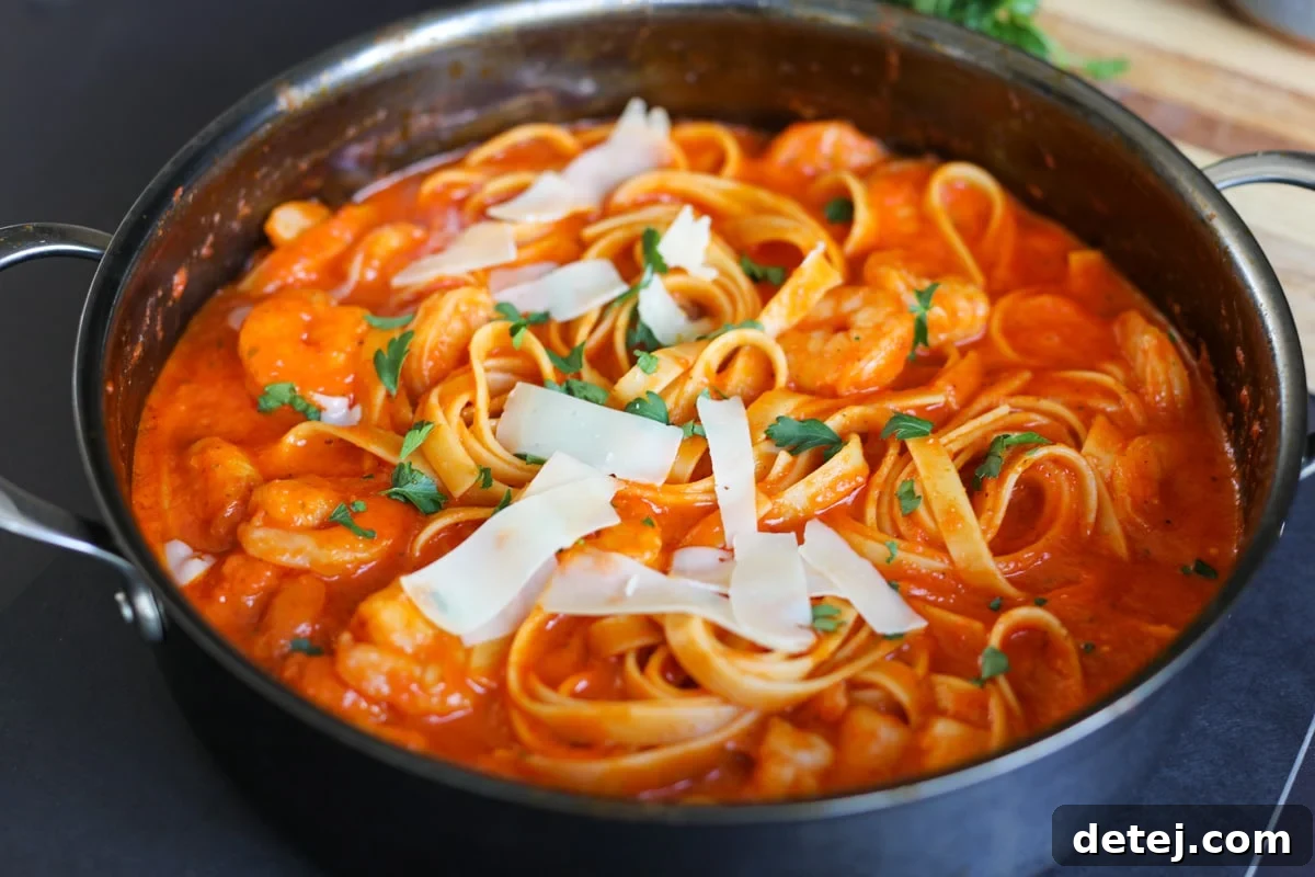 Smoky Red Pepper Shrimp Pasta 4 Shrimp pasta with roasted red pepper sauce in a pan, garnished with shaved parmesan cheese and fresh parsley.