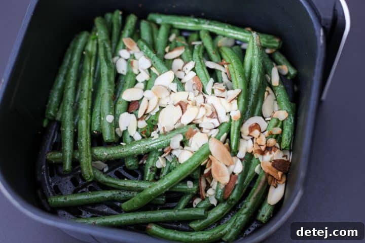 green beans cooking in the air fryer with almonds.