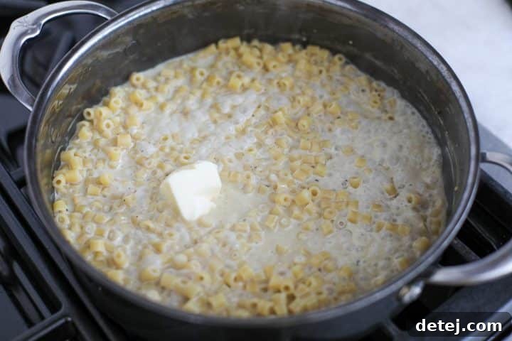 Cold butter cubes melting into the creamy cacio e pepe sauce, creating a smooth emulsion.