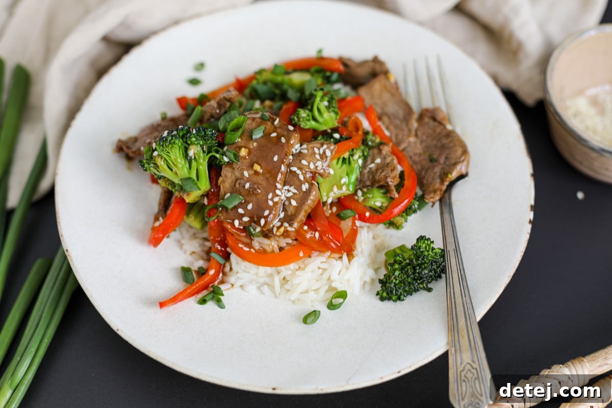 Close-up of a plate with Beef and Broccoli stir-fry, garnished with sesame seeds.