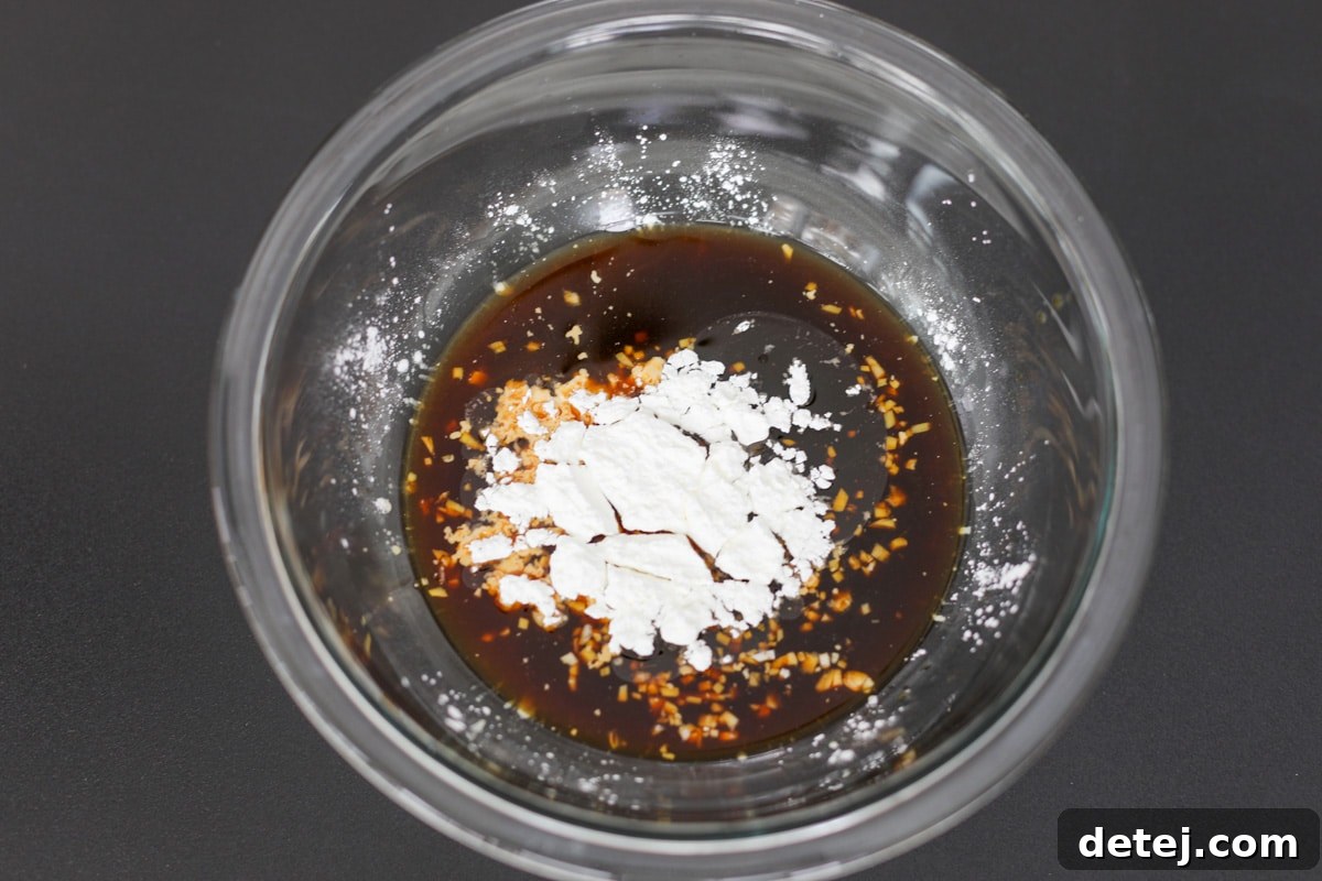 Stir-fry sauce ingredients combined in a glass bowl with a whisk.