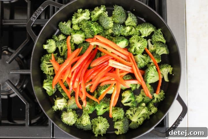 Broccoli and red bell peppers sautéing together in a pan.
