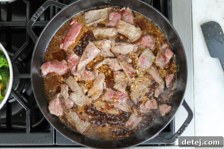 Seared beef with sauce being added to the pan.