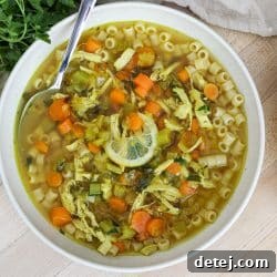 Lemon Chicken Soup in a bowl next to crusty bread.
