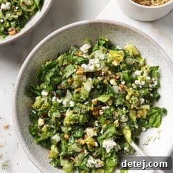 A vibrant Greek salad in a bowl, featuring crisp lettuce, green onions, feta, and pistachios.