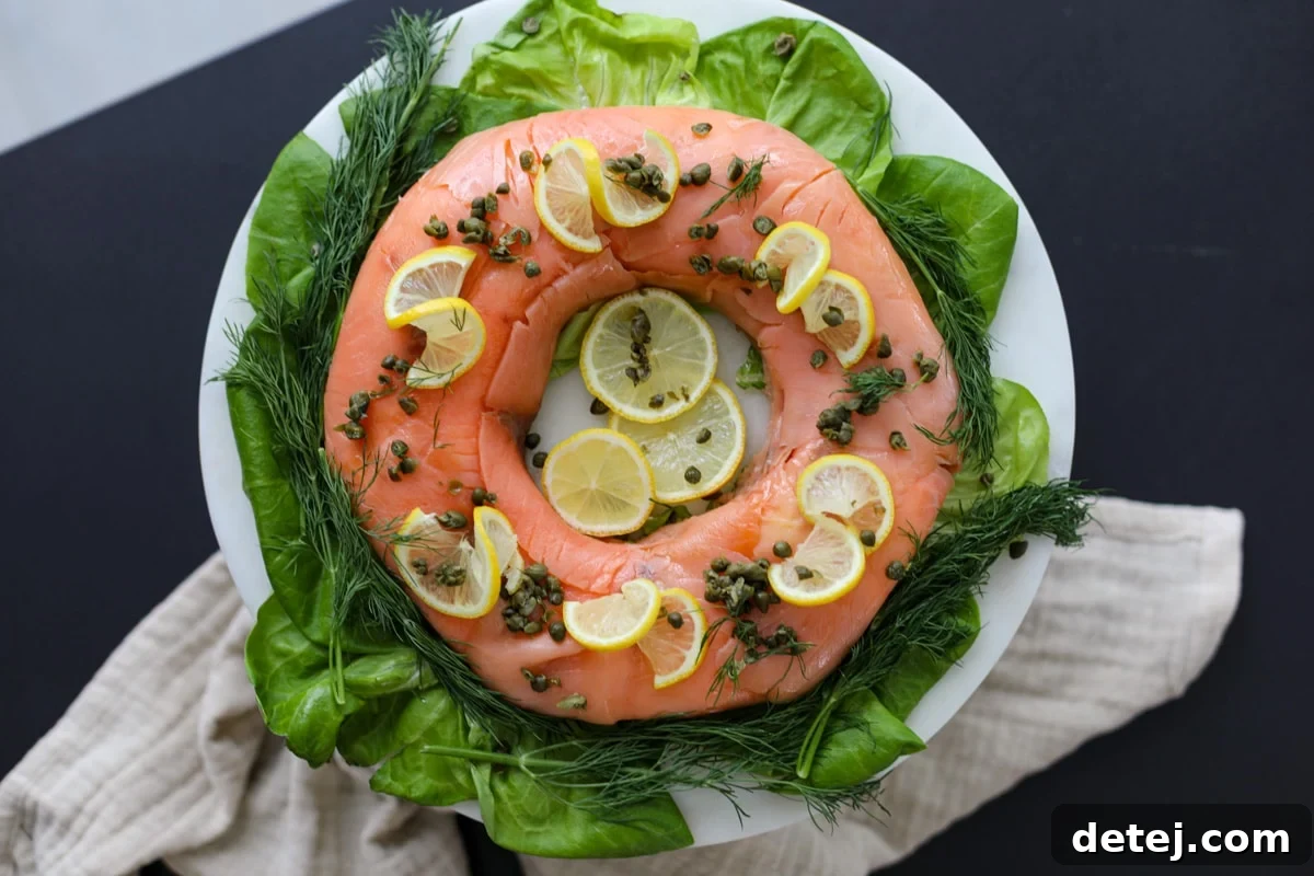 A stunning Smoked Salmon Ring, garnished with fresh dill, capers, and lemon slices, served on a white platter with butter lettuce.
