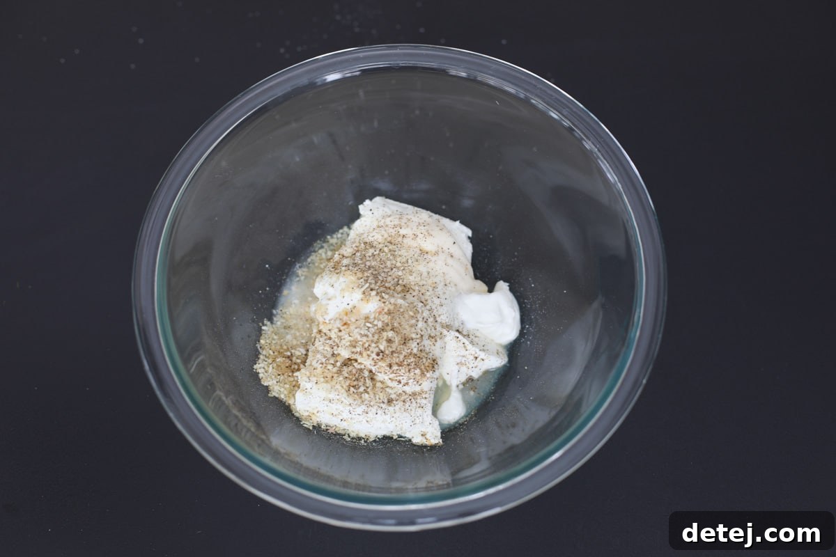 A bowl of unmixed cream cheese filling ingredients, including softened cream cheese, mayonnaise, sour cream, and seasonings.