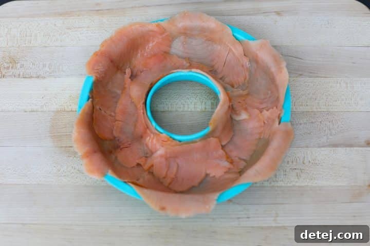 Smoked salmon meticulously lining the interior of a donut mold, with edges overlapping.