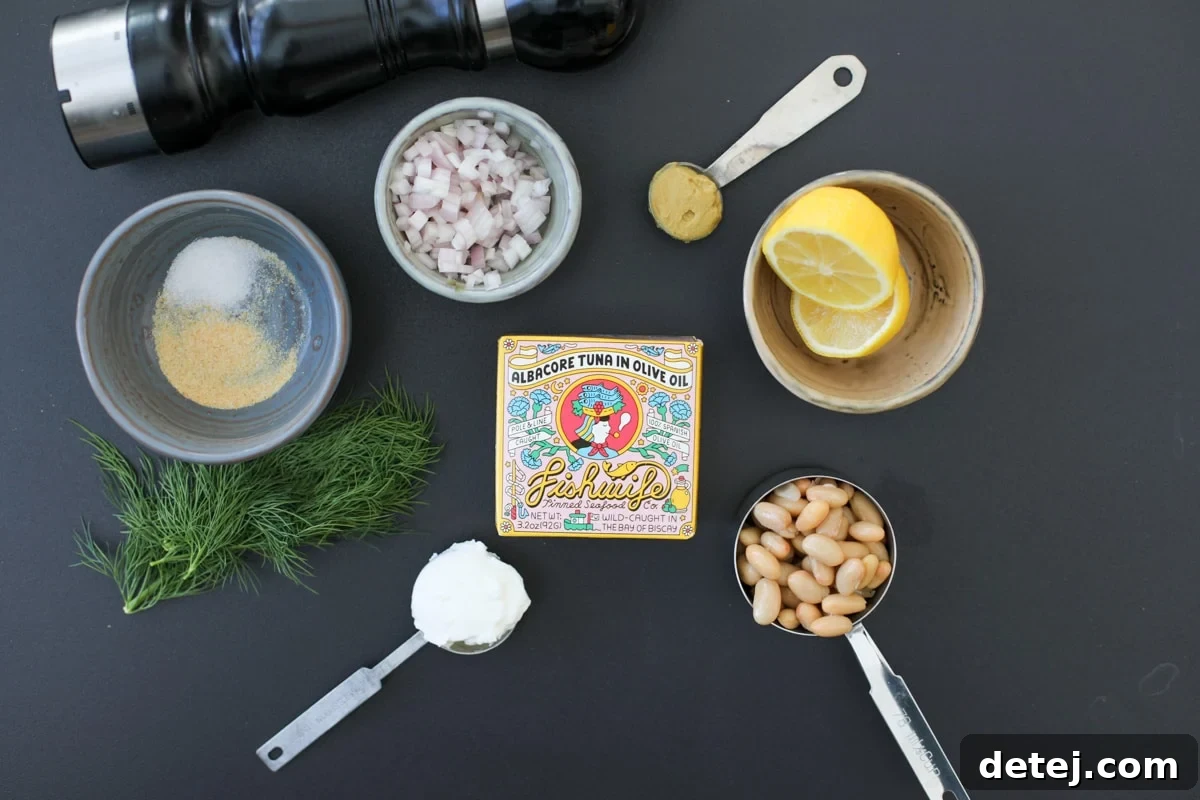 Fresh ingredients laid out for Smashed Bean Tuna Salad, including canned tuna, beans, lemon, and dill.