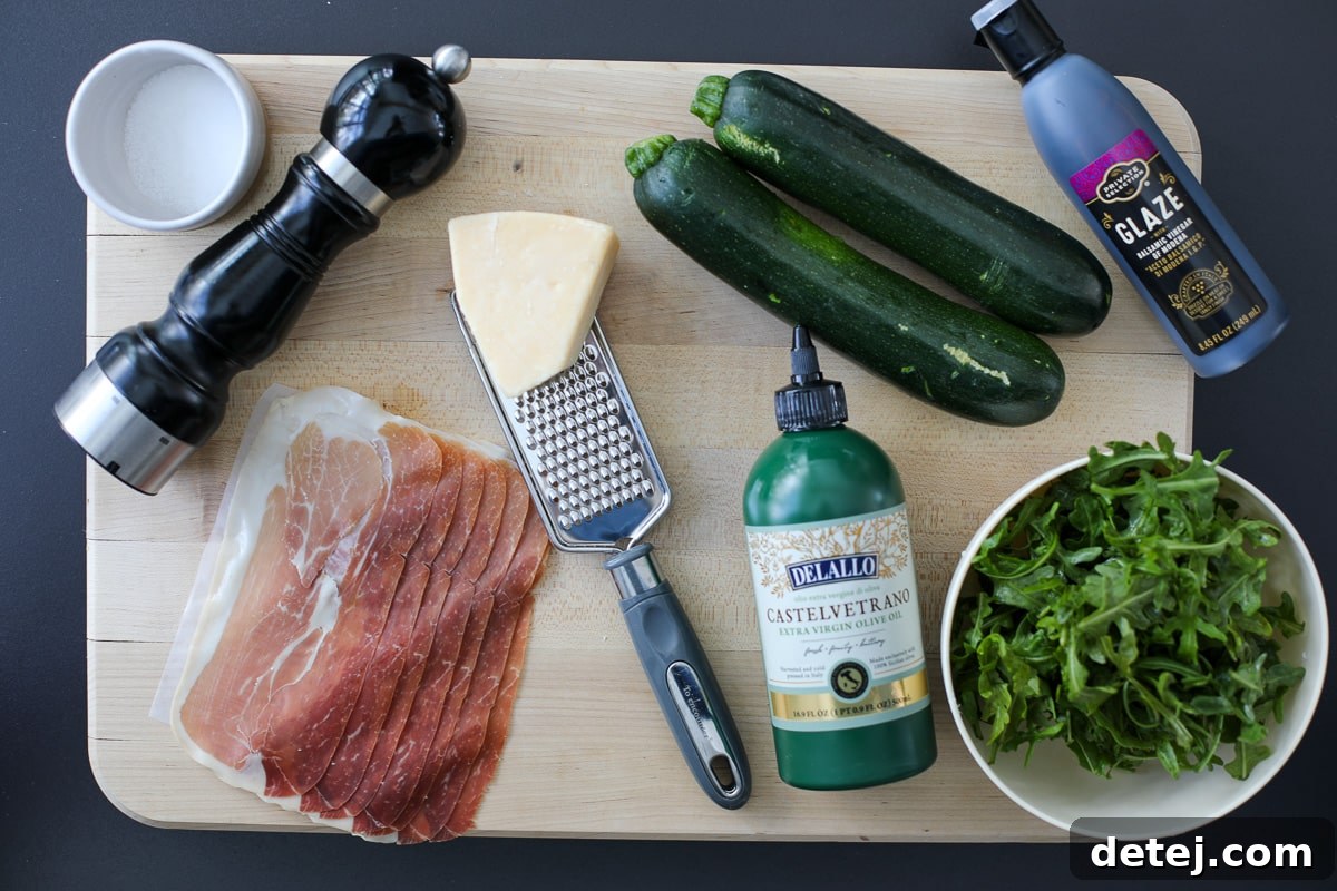 Ingredients for grilled zucchini roll ups laid out on a cutting board: zucchini, prosciutto, arugula, parmesan, balsamic glaze.