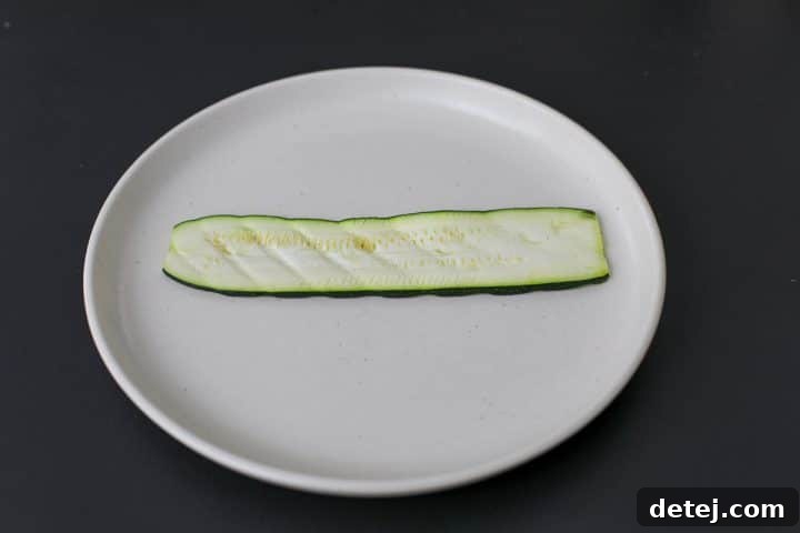 A single slice of grilled zucchini laid flat, ready for assembly.