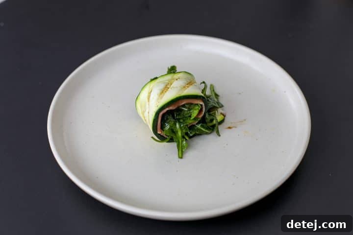 A beautifully rolled up grilled zucchini with prosciutto and arugula filling.
