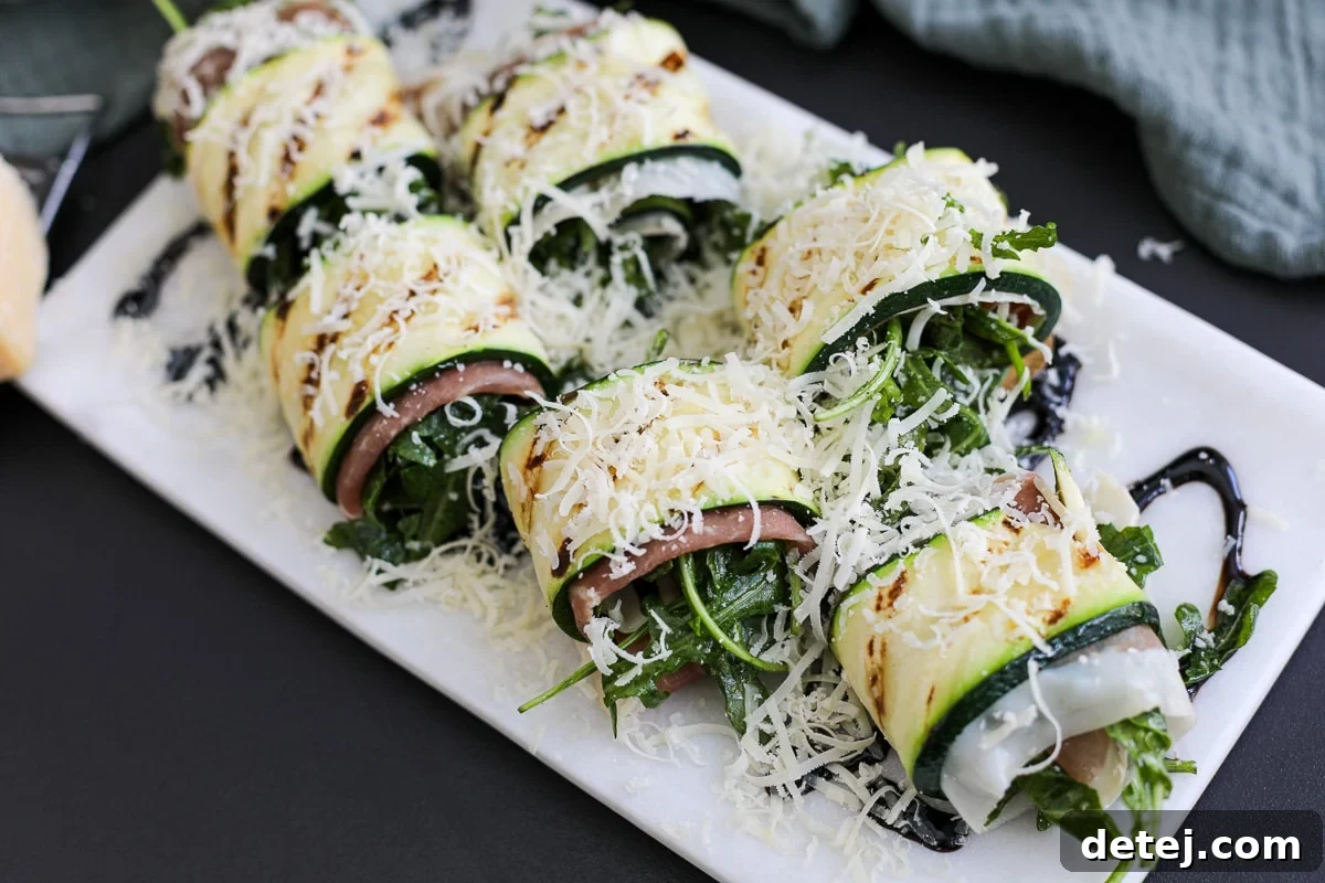 A close-up shot of grilled zucchini roll ups on a white plate, ready to be enjoyed.