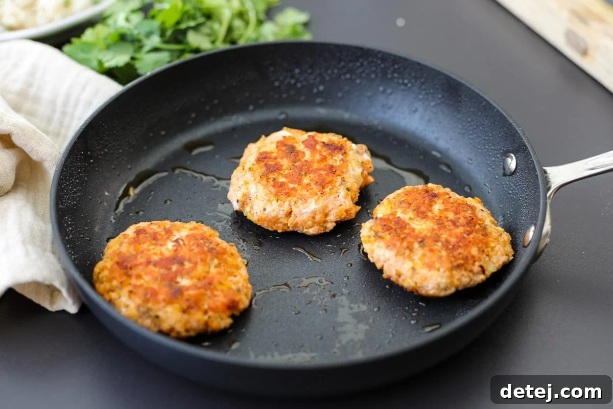 Close-up of a perfectly cooked spicy salmon burger, showcasing its crispy exterior and succulent interior.