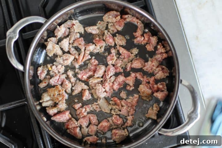 Raw Italian sausage being added to a hot sauté pan with avocado oil.