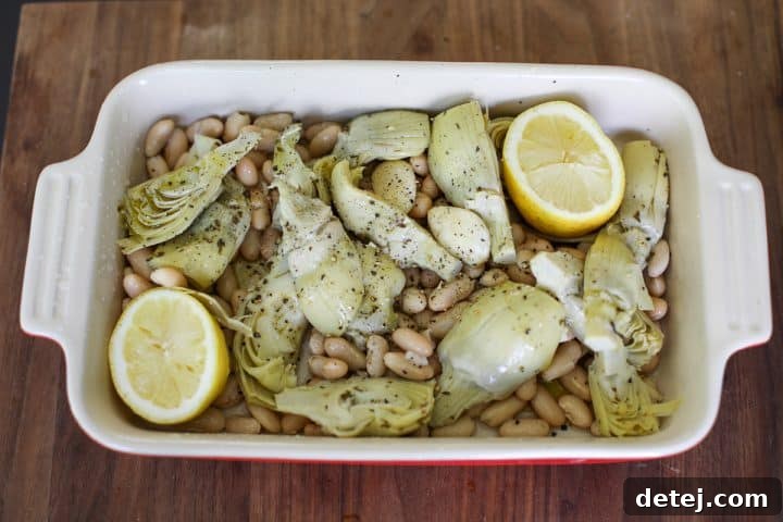 Artichokes and beans in a baking dish before roasting.