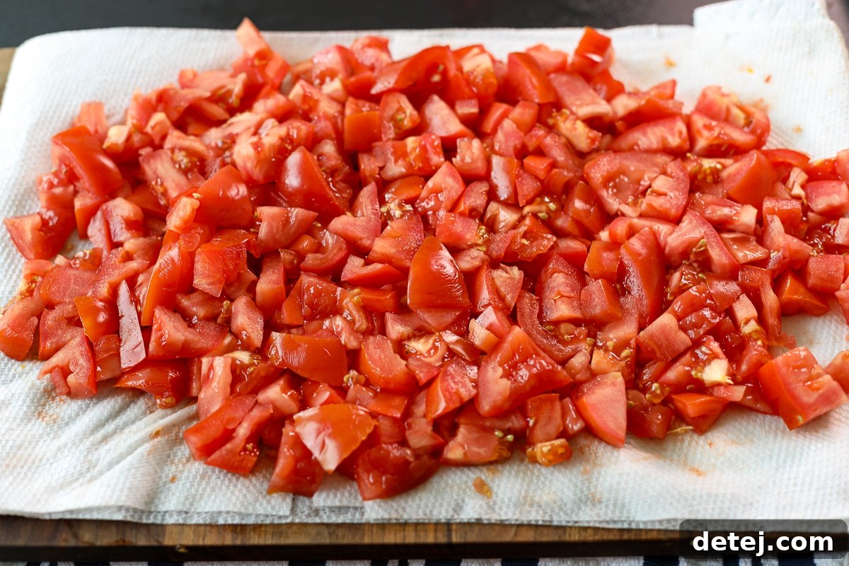 Medium diced tomatoes resting on layers of paper towel to absorb moisture.