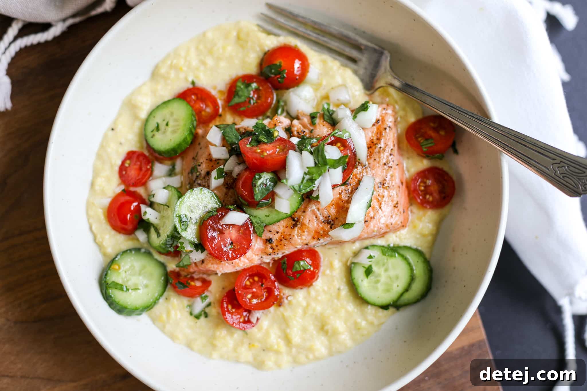 Grilled salmon served over a bed of creamy corn puree, garnished with a fresh tomato and cucumber salad in a rustic bowl, embodying a perfect summer meal.