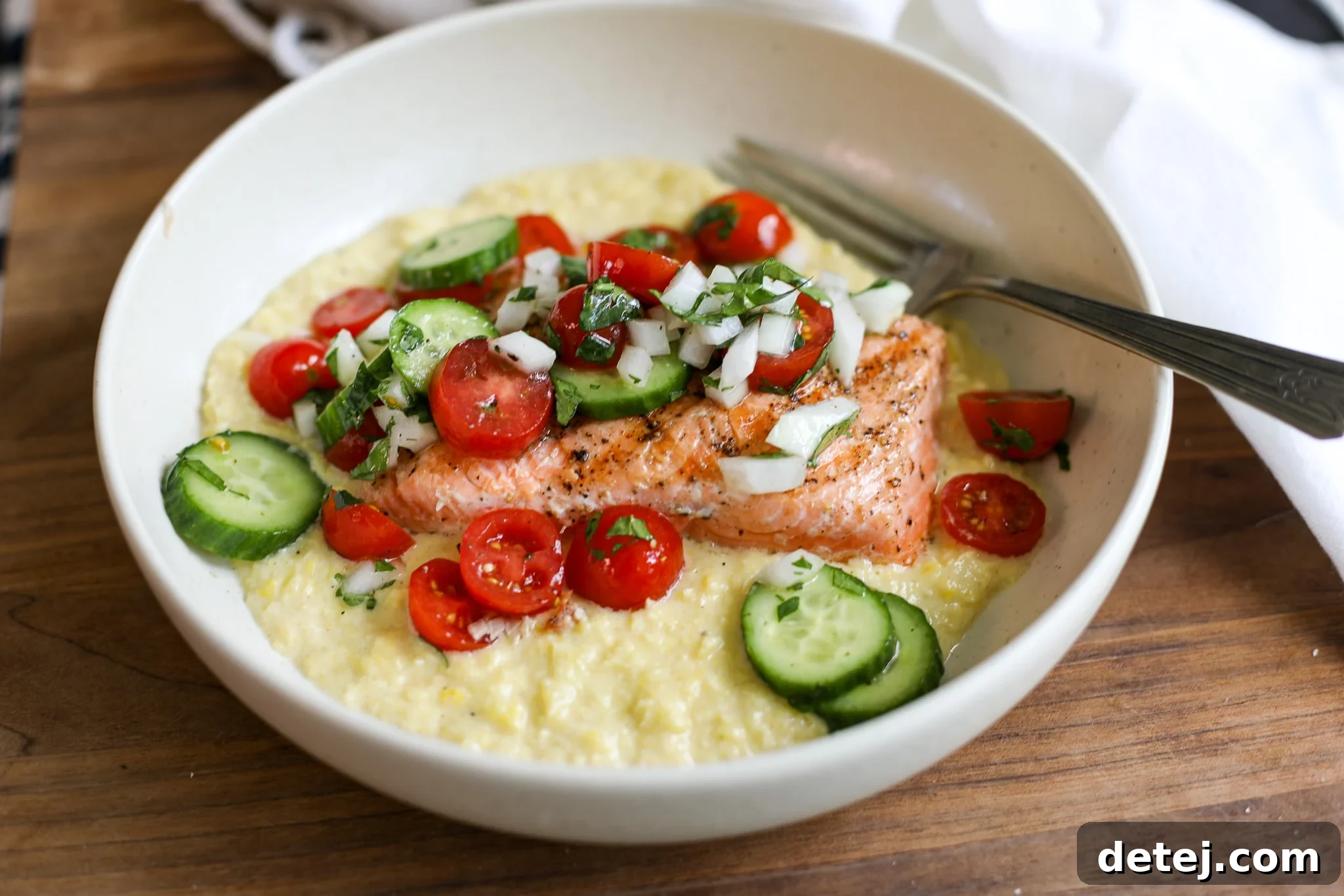 A completed dish of grilled salmon, creamy corn puree, and fresh tomato salad, artfully arranged and ready to be enjoyed.
