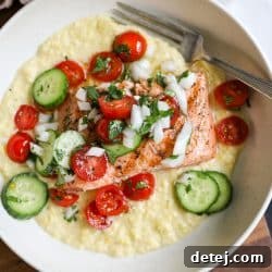 Grilled salmon over creamed corn and tomato salad in a bowl.