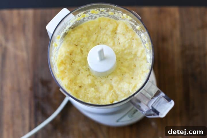 Blended corn in a food processor, showing a creamy, smooth texture before being cooked into a puree.