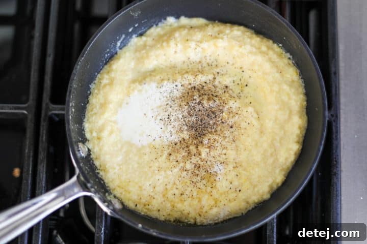 Creamy corn puree simmering in a nonstick pan, with a spoon stirring the mixture to prevent sticking.