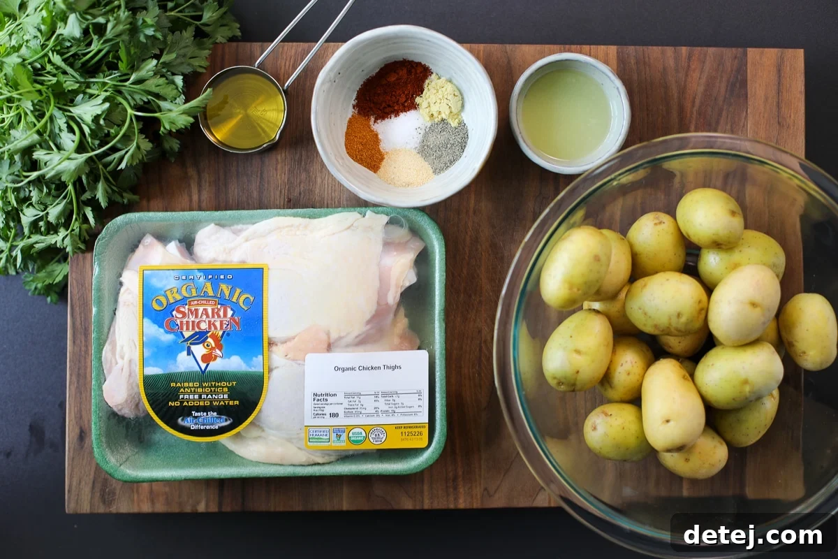 A selection of fresh ingredients including chicken thighs, baby potatoes, lemons, and spices laid out for one pan roasted chicken and potatoes.